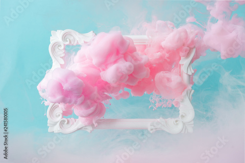 White vintage frame on pastel blue background with abstract pink cloud shapes. Minimal border composition. photo