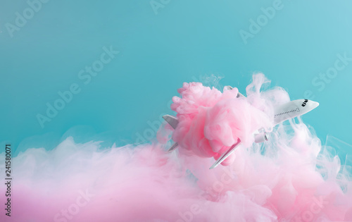 Fototapeta Samolot pasażerski odrzutowy latający przez pastelowe różowe chmury. Minimalna koncepcja transportu, podróży lub wakacji.