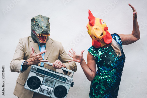 Crazy senior couple dancing for new year's eve party wearing t-rex and chicken mask