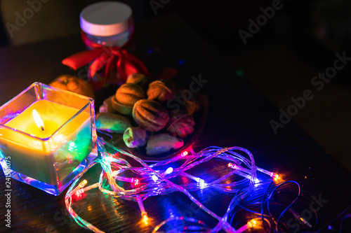 Top view. Christmas New Year Composition with Tangerines candle  garlands  colorful lights  selective focus Black Background Holiday Decoration  copy space