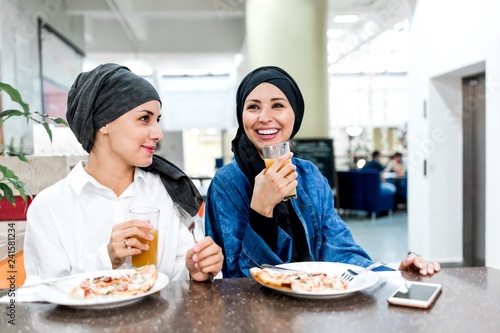 Photography Two Muslim girls eat in a cafe celebrating international women's day