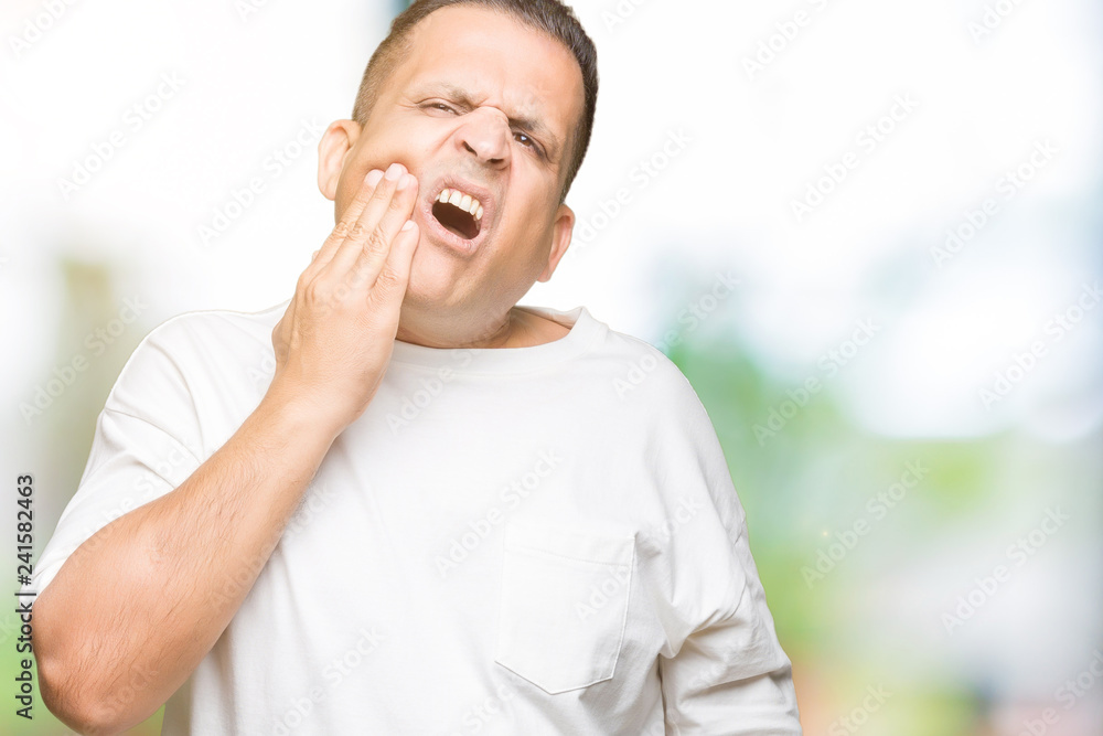 Middle age arab man wearig white t-shirt over isolated background touching mouth with hand with painful expression because of toothache or dental illness on teeth. Dentist concept.