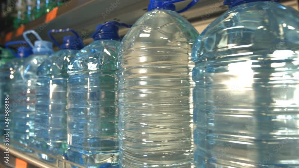 Bottled water.
Water bottles stand on the shelf in store. Hand takes one bottle. Bottled water.
Water bottles stand on the shelf in store. Hand takes one bottle.