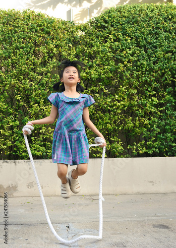 Portrait of asian  little girl jumping rope in the park.