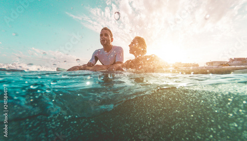 Fit couple surfing at sunset