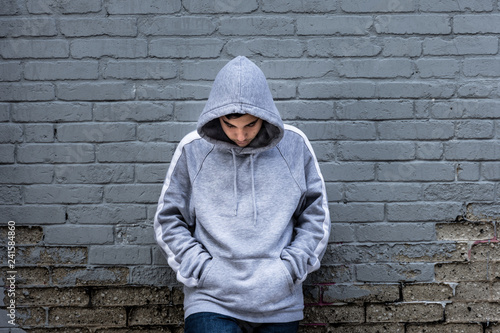 Lonely boy leaning against an urban wall