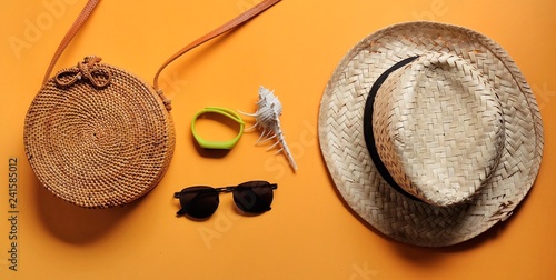 Luggage, watch, conch shell, weave hat,sunglasses including items to go to the sea on orange background.Summer vacation concept background. Travel items on the beach. - Image