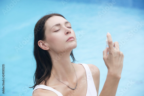 Woman spraying facial mist on her face, summertime skin care concept