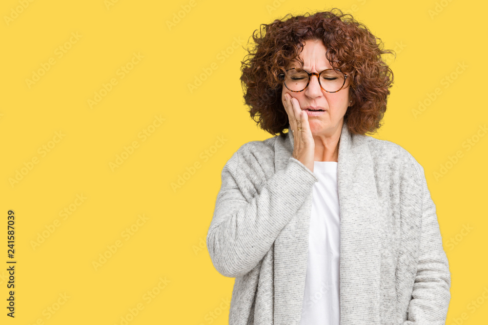 Beautiful middle ager senior woman wearing jacket and glasses over isolated background touching mouth with hand with painful expression because of toothache or dental illness on teeth Beautiful middle ager senior woman wearing jacket and glasses over isolated background touching mouth with hand with painful expression because of toothache or dental illness on teeth