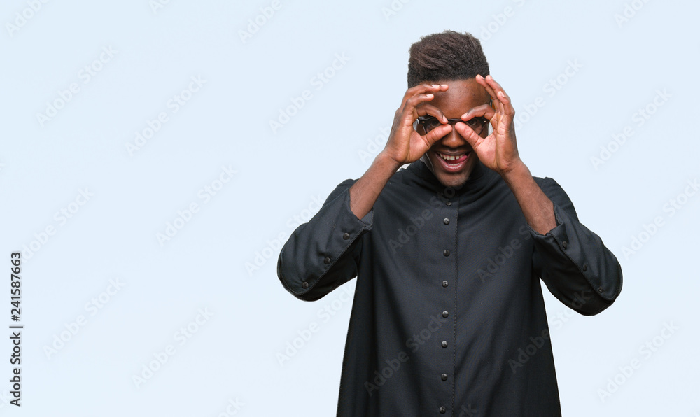 Young african american priest man over isolated background doing ok gesture like binoculars sticking tongue out, eyes looking through fingers. Crazy expression. Young african american priest man over isolated background doing ok gesture like binoculars sticking tongue out, eyes looking through fingers. Crazy expression.