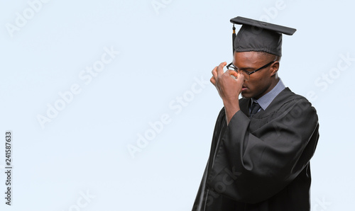 Young graduated african american man over isolated background tired rubbing nose and eyes feeling fatigue and headache. Stress and frustration concept.