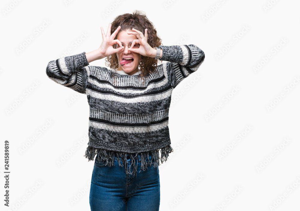 Beautiful brunette curly hair young girl wearing glasses over isolated background doing ok gesture like binoculars sticking tongue out, eyes looking through fingers. Crazy expression. Beautiful brunette curly hair young girl wearing glasses over isolated background doing ok gesture like binoculars sticking tongue out, eyes looking through fingers. Crazy expression.