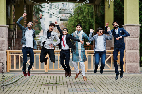 Group of six south asian indian mans in traditional, casual and business wear jumping in the air together.