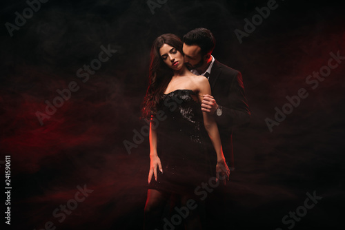 Fototapet handsome man hugging seductive woman in red smoky room