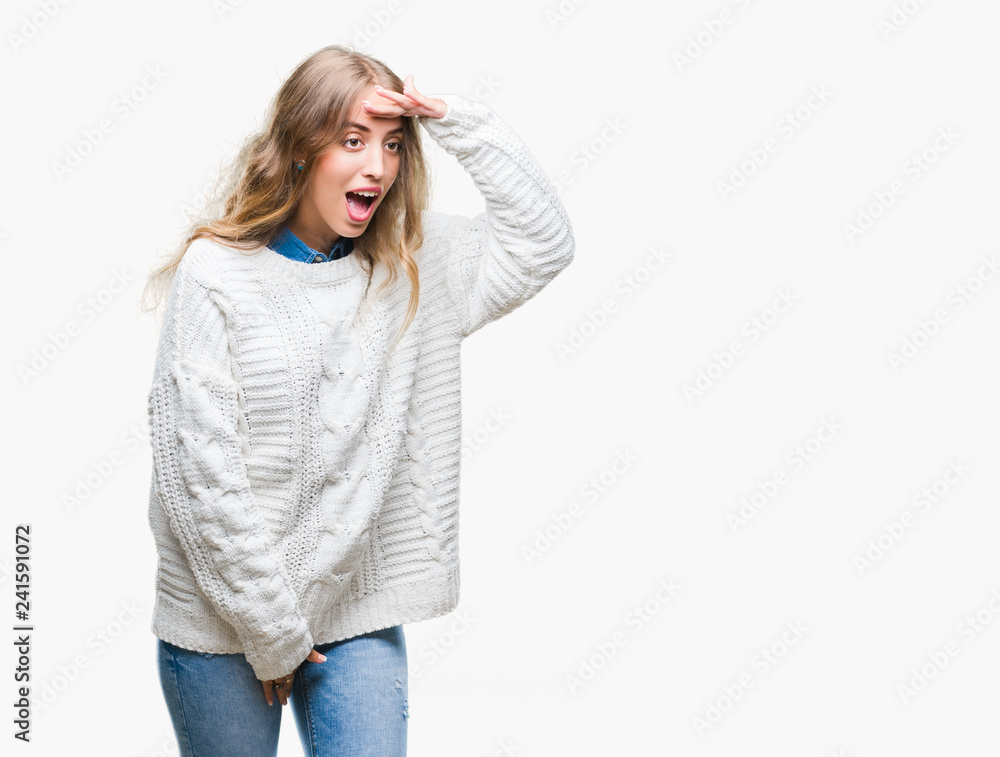 Beautiful young blonde woman wearing winter sweater over isolated background very happy and smiling looking far away with hand over head. Searching concept. Beautiful young blonde woman wearing winter sweater over isolated background very happy and smiling looking far away with hand over head. Searching concept.
