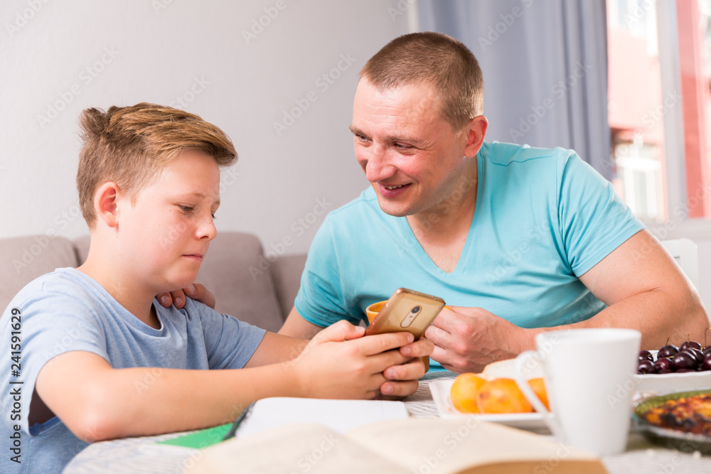 Obraz premium Man with his son are playing on phone together