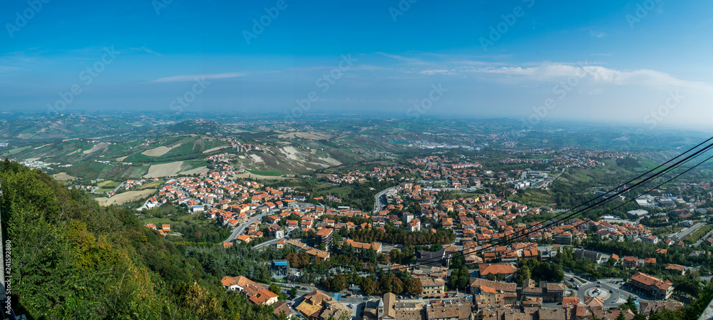 Fototapeta premium panoramic view on the hilly plain of the foothills of the Apennines with city and funicular cable way from the mountain Monte Titano, old city of republic of san marino