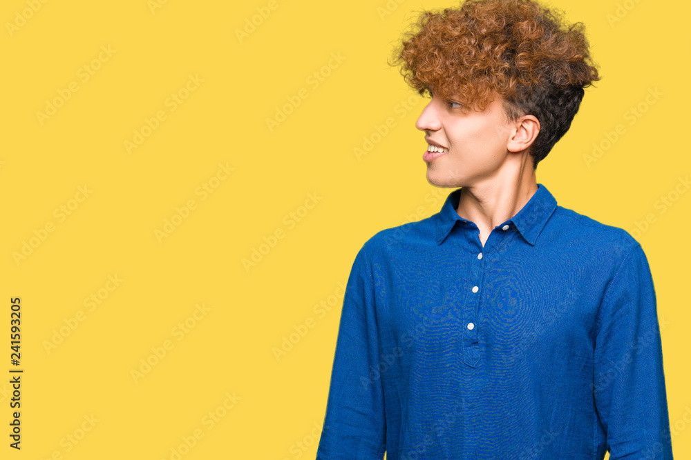 Obraz premium Young handsome elegant man with afro hair looking away to side with smile on face, natural expression. Laughing confident.