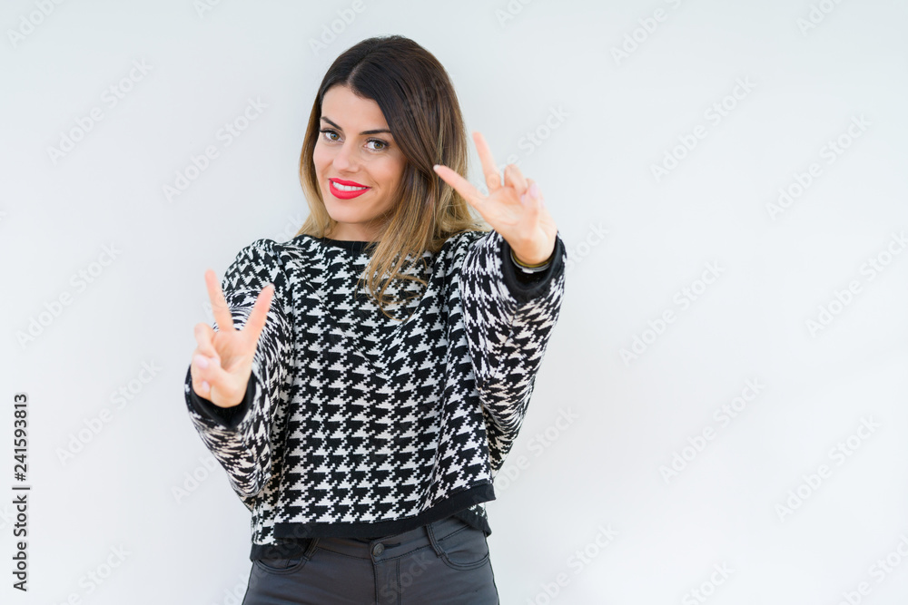 Young woman wearing casual sweater over isolated background smiling looking to the camera showing fingers doing victory sign. Number two. Young woman wearing casual sweater over isolated background smiling looking to the camera showing fingers doing victory sign. Number two.