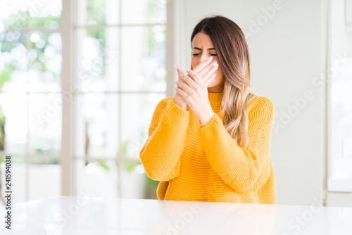 Young beautiful woman wearing winter sweater at home Suffering pain on hands and fingers, arthritis inflammation