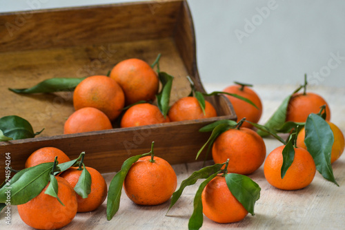 Fresh mandarin oranges fruit or tangerines with leaves on the wooden box on the table. 