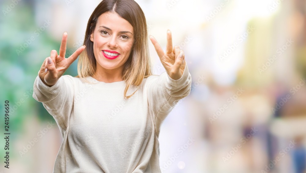 Young beautiful woman casual white sweater over isolated background smiling looking to the camera showing fingers doing victory sign. Number two. Young beautiful woman casual white sweater over isolated background smiling looking to the camera showing fingers doing victory sign. Number two.