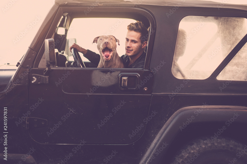 Couple of crazy funny friends driving black car together: man and shouting hungry dog traveling with off road vehicle - vintage filter and brown colors for transport funny concept