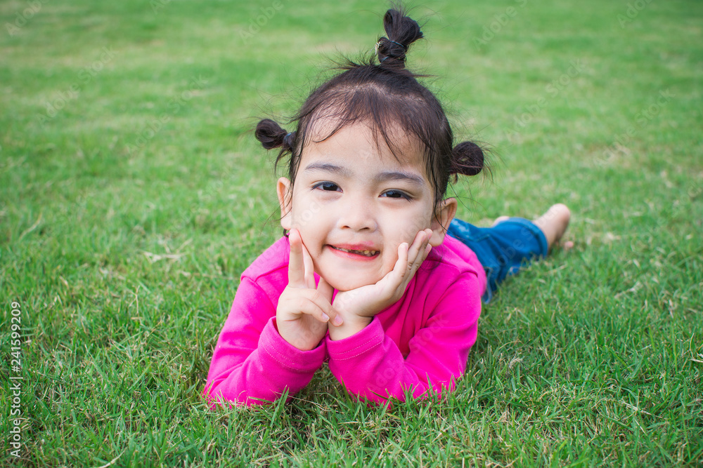 happy little girl lying on green grass and playing in the park. soft focus. happy little girl lying on green grass and playing in the park. soft focus.