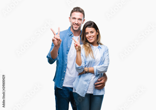 Young couple in love over isolated background smiling with happy face winking at the camera doing victory sign. Number two.