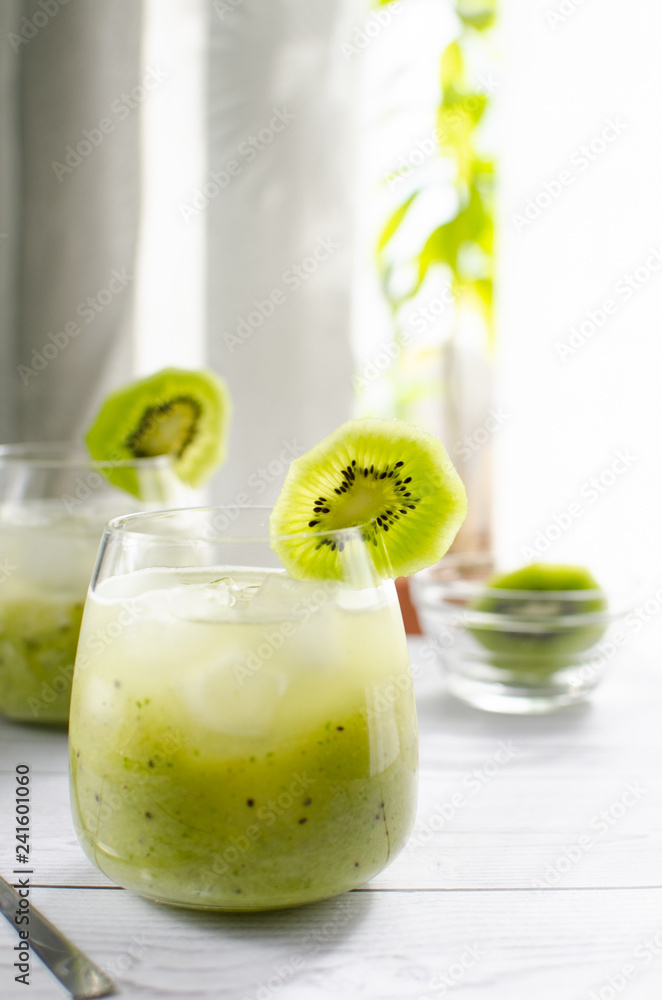 A glass of freshly squeezed kiwi juice is on a wooden table A glass of freshly squeezed kiwi juice is on a wooden table