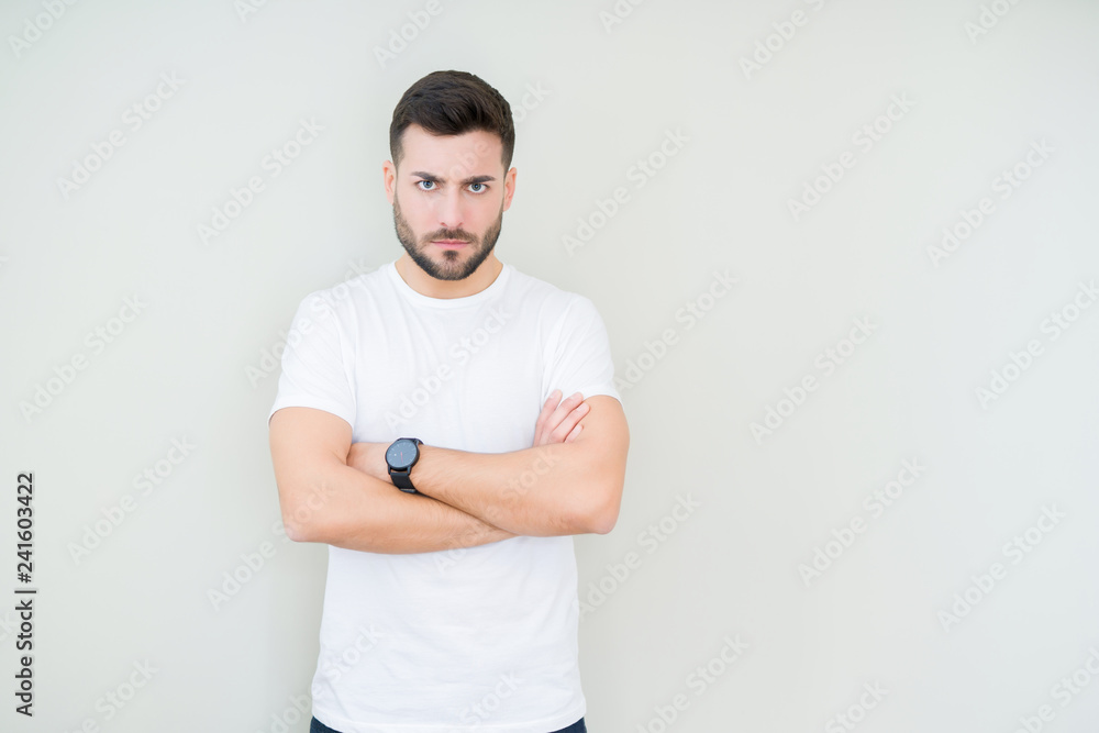 Young handsome man wearing casual white t-shirt over isolated background skeptic and nervous, disapproving expression on face with crossed arms. Negative person. Young handsome man wearing casual white t-shirt over isolated background skeptic and nervous, disapproving expression on face with crossed arms. Negative person.