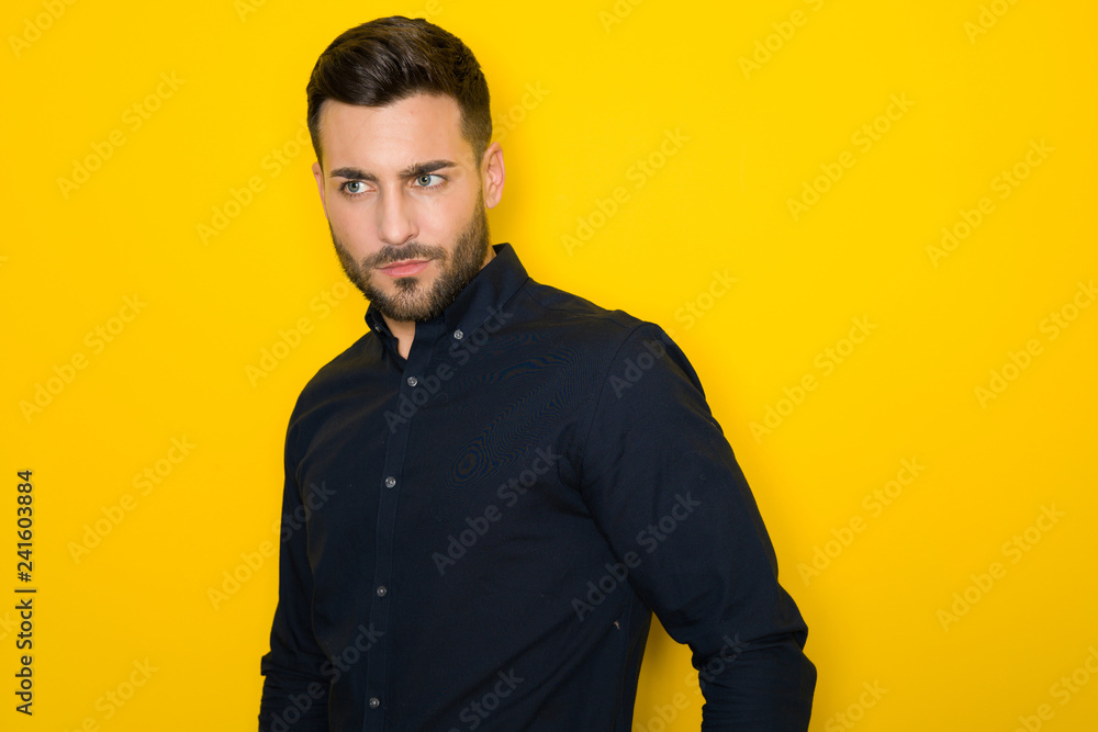 Fototapeta premium Young handsome man possing and modeling over yellow isolated background