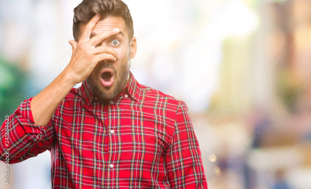 Young handsome man over isolated background peeking in shock covering face and eyes with hand, looking through fingers with embarrassed expression. Young handsome man over isolated background peeking in shock covering face and eyes with hand, looking through fingers with embarrassed expression.