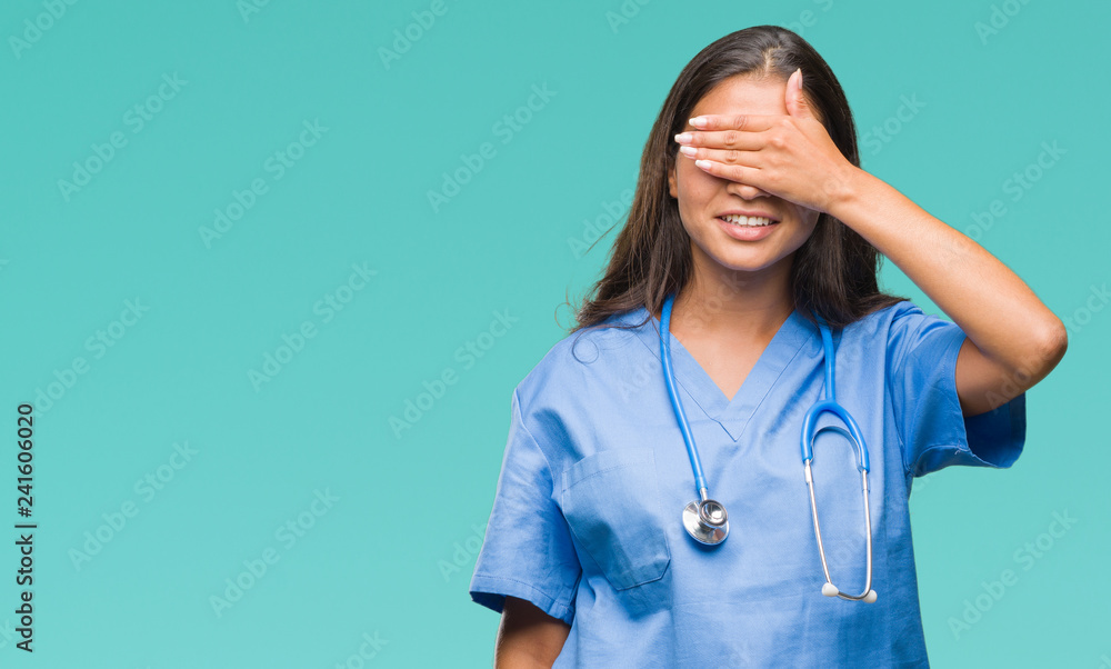 Young arab doctor surgeon woman over isolated background smiling and laughing with hand on face covering eyes for surprise. Blind concept. Young arab doctor surgeon woman over isolated background smiling and laughing with hand on face covering eyes for surprise. Blind concept.