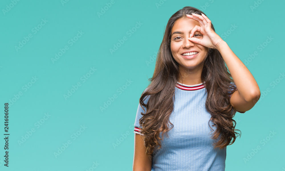 Young beautiful arab woman over isolated background doing ok gesture with hand smiling, eye looking through fingers with happy face. Young beautiful arab woman over isolated background doing ok gesture with hand smiling, eye looking through fingers with happy face.