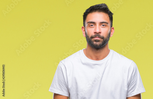 Adult hispanic man over isolated background with serious expression on face. Simple and natural looking at the camera.