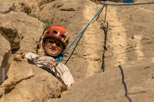 boy climbed on a mountain climbing looking at camera smiling