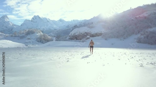 Young man walking on the ice. Top view of  frozen Lake Bukumir in Montenegro. Aerial shooting winter mountain landscape on sunny day.
 photo