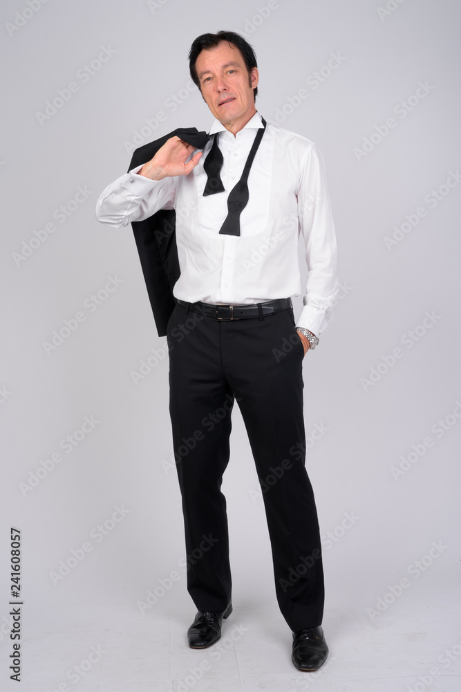 Full body shot of mature handsome businessman carrying jacket over shoulder Full body shot of mature handsome businessman carrying jacket over shoulder