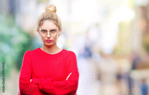 Young beautiful blonde woman wearing red sweater and glasses over isolated background skeptic and nervous, disapproving expression on face with crossed arms. Negative person.