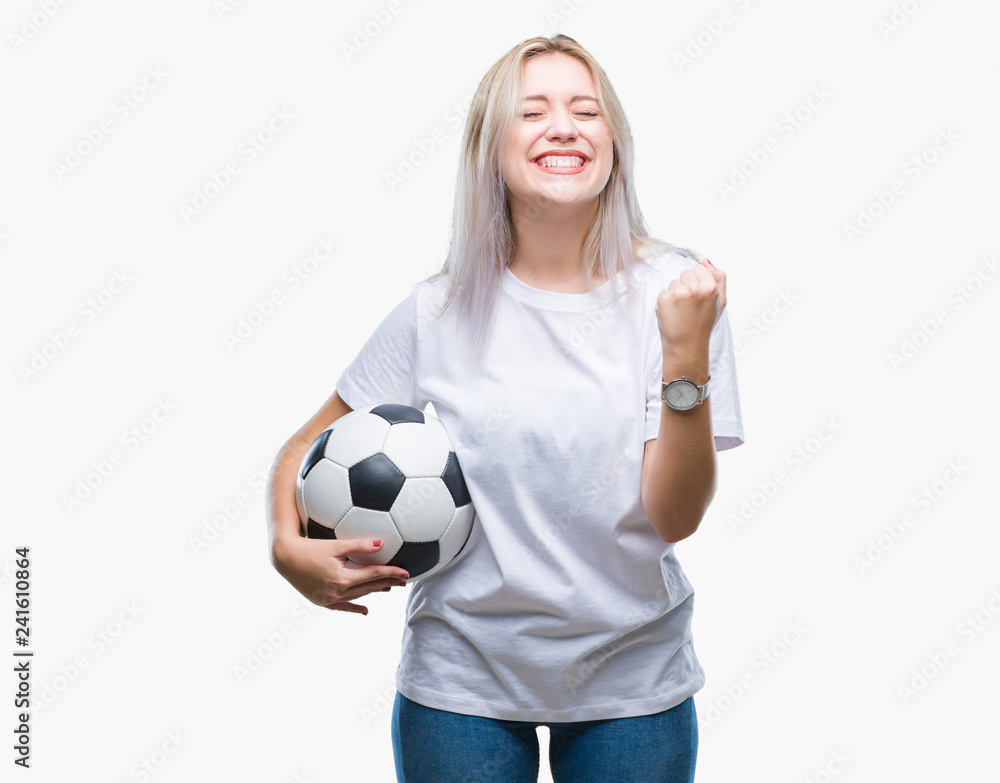 Young blonde woman holding soccer football ball over isolated background screaming proud and celebrating victory and success very excited, cheering emotion