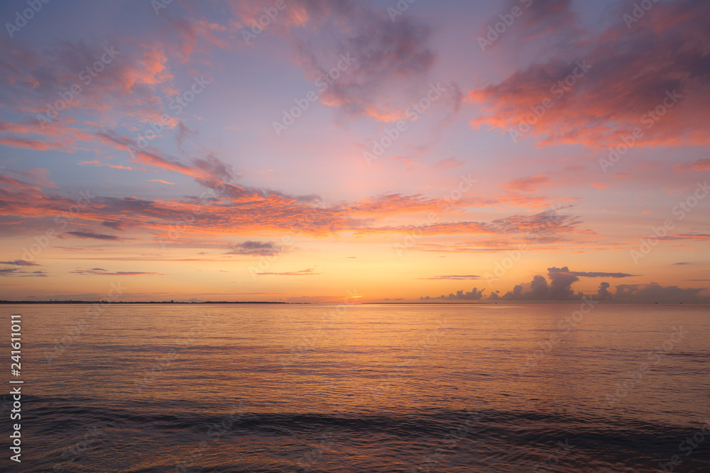 Colourful orange and pink sunset with bright sky and beautiful clouds over Baltic sea.