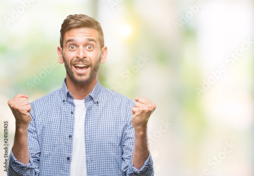 Young handsome man wearing white t-shirt over isolated background celebrating surprised and amazed for success with arms raised and open eyes. Winner concept.