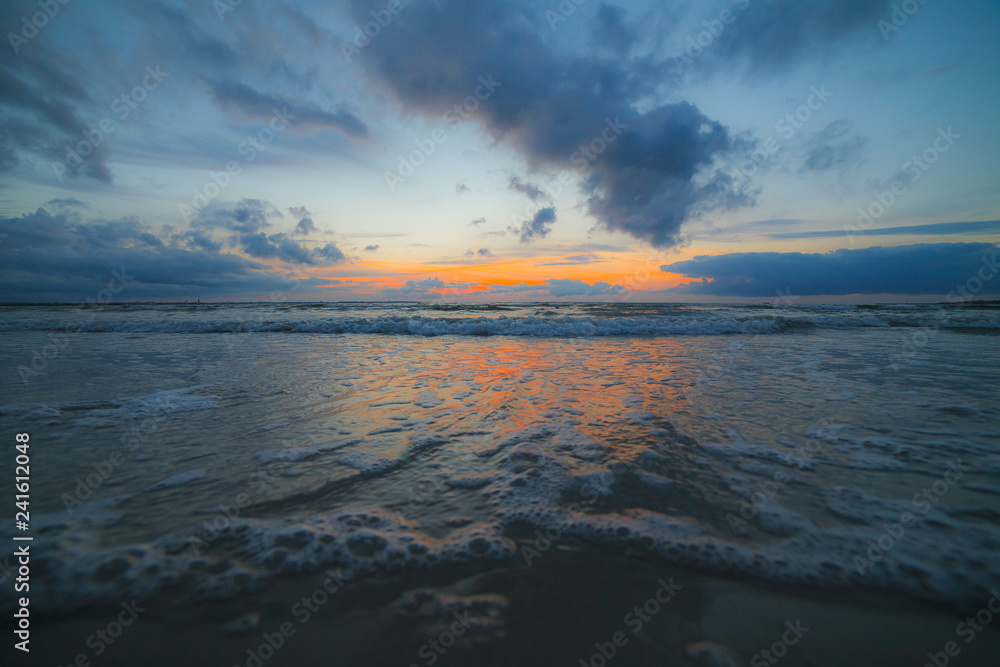 Calm Baltic sea at sunset with beautiful clouds and low waves
