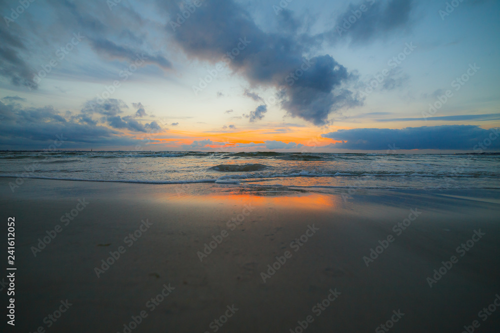 Calm Baltic sea at sunset with beautiful clouds and low waves