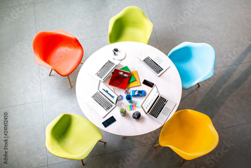 Top view on the working place with round table and colorful chairs in the office