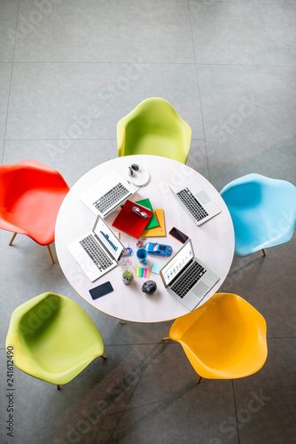 Top view on the working place with round table and colorful chairs in the office