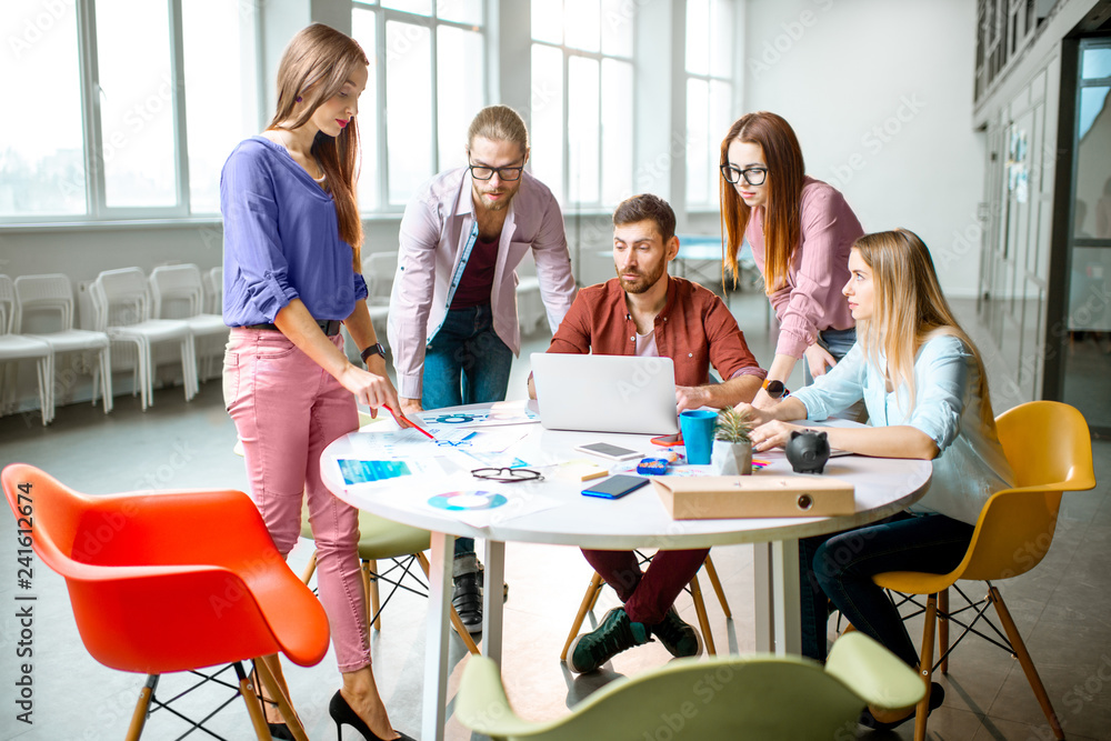 Group of a young coworkers dressed casually working together with laptops in the modern office Group of a young coworkers dressed casually working together with laptops in the modern office
