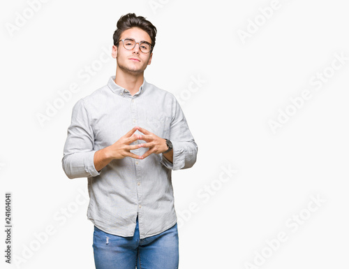 Young handsome man wearing glasses over isolated background Hands together and fingers crossed smiling relaxed and cheerful. Success and optimistic