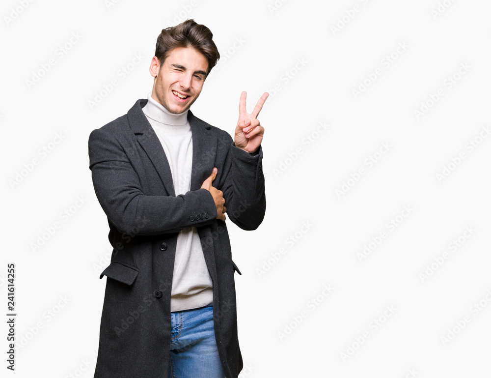 Young elegant man wearing winter coat over isolated background smiling with happy face winking at the camera doing victory sign. Number two. Young elegant man wearing winter coat over isolated background smiling with happy face winking at the camera doing victory sign. Number two.